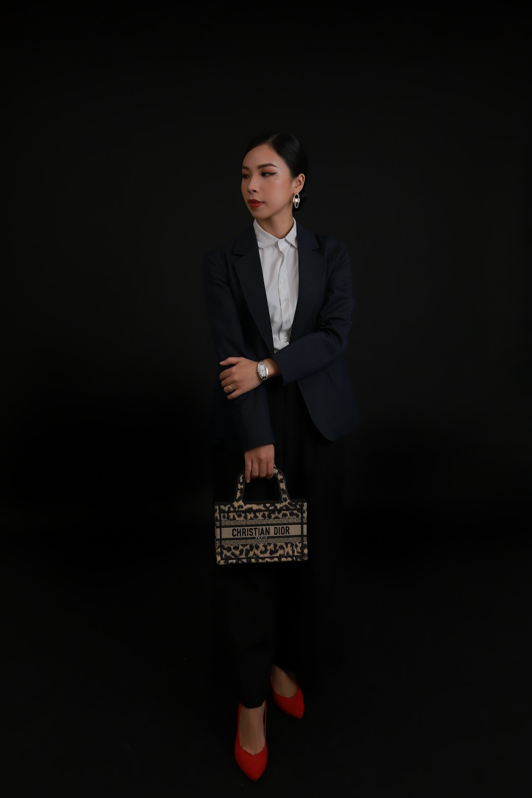 Model wearing black tailored blazer with cream silk blouse and gold statement jewelry from Maison Lyra